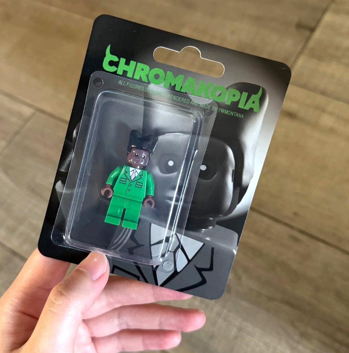 Tyler The Creator Chromakopia Custom Minifigure in green suit, blister packaging, wooden background.