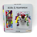 Kanye West 808s & Heartbreak minifigure, grey suit, red heart brooch, collector packaging.