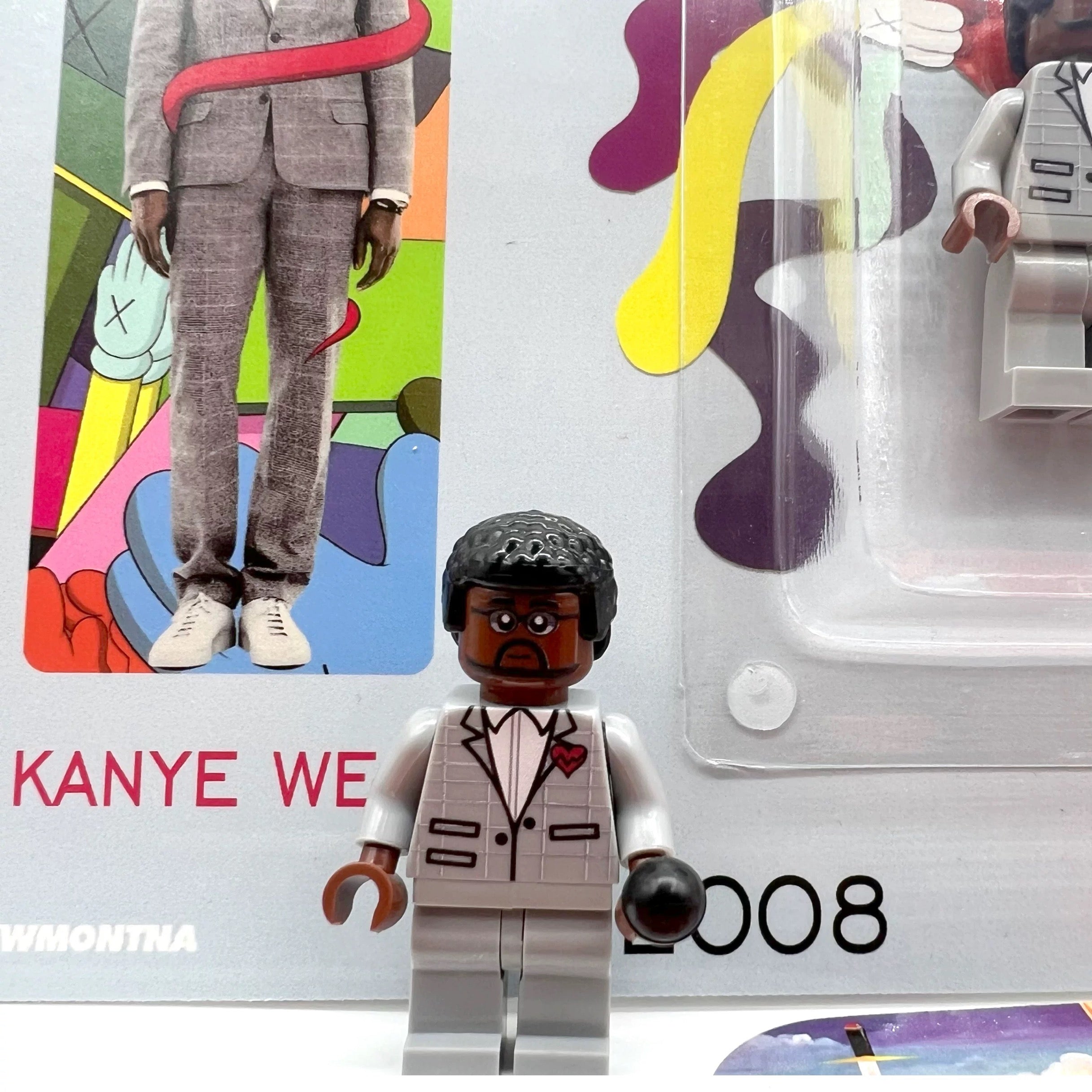 Kanye West "808s & Heartbreak" custom minifigure in grey suit with red heart brooch, collector packaging.
