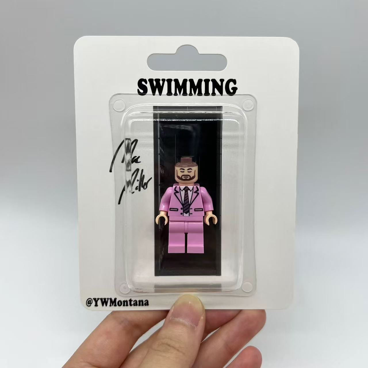 Mac Miller "Swimming" minifigure in pink suit, white shirt; blister packaging with album-themed design.